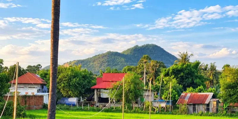 Dorpshuizen onder een beboste heuvel op het platteland van Kampot